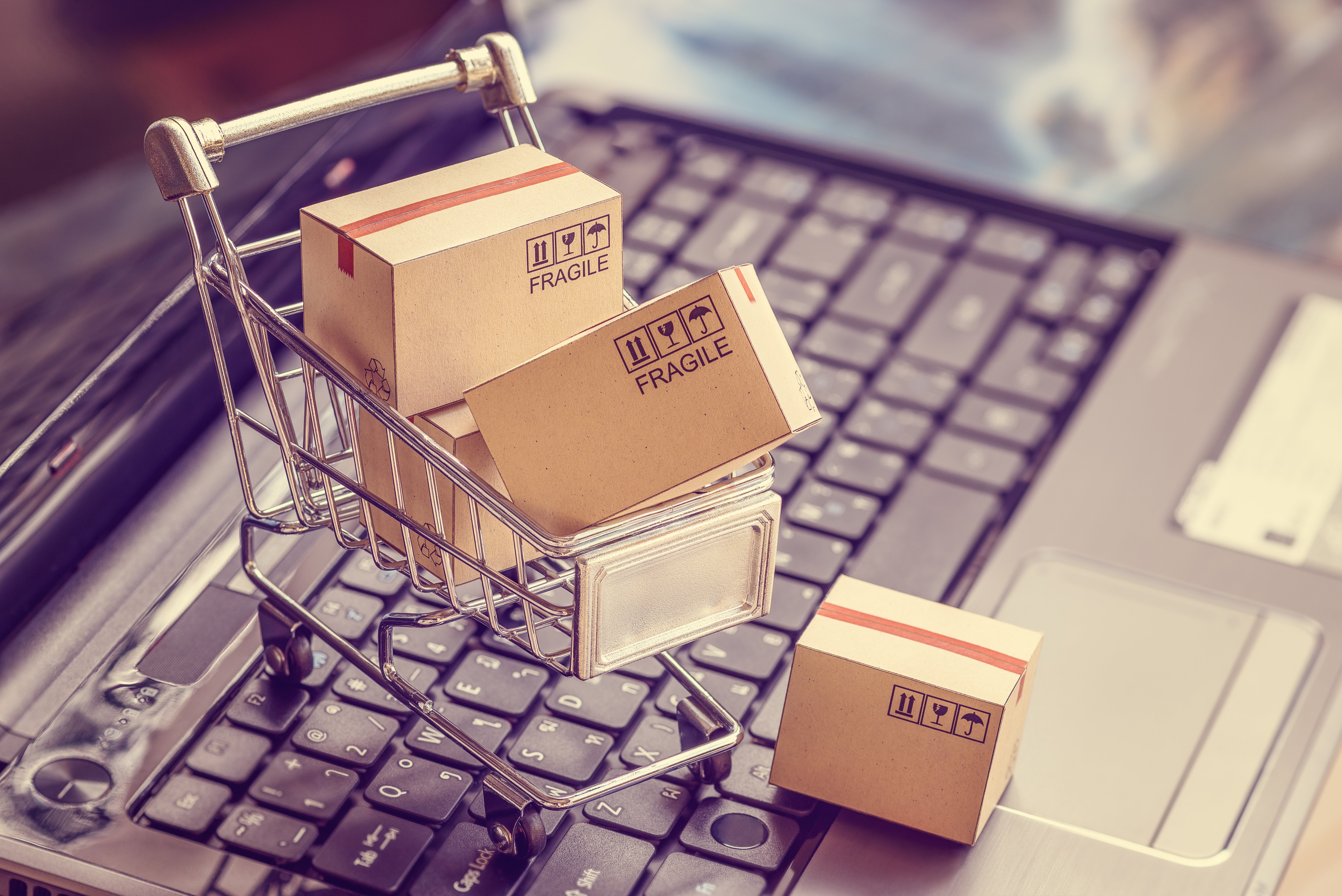 Photo of Laptop with a Shopping Cart Filled With Boxes - Smart Warehousing